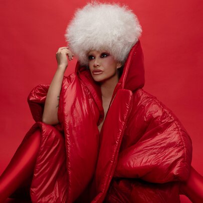Jazz singer Lady Blackbird in a white curly wig and puffy red outfit with an exaggerated collar turned up. 