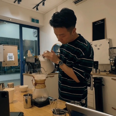 Barista pouring water into a coffee jug in an industrial kitchen.