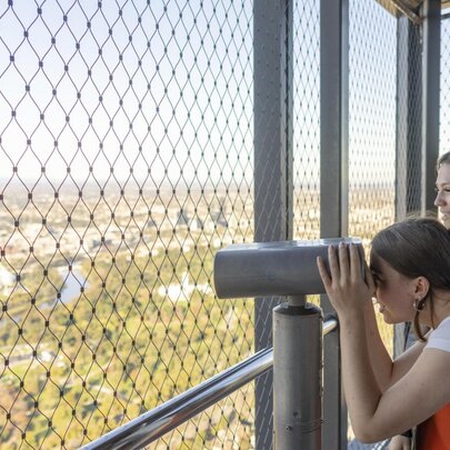People looking through binoculars at a viewing platform overlooking Melbourne.
