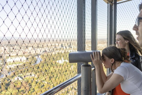 People looking through binoculars at a viewing platform overlooking Melbourne.