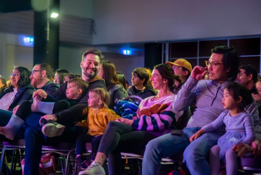 An audience of adults and kids watching and smiling.