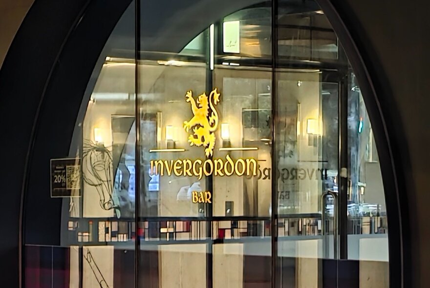 A close up of the arched window at Invergordon Bar, with the Invergordon logo and a Scottish tartan on the window.