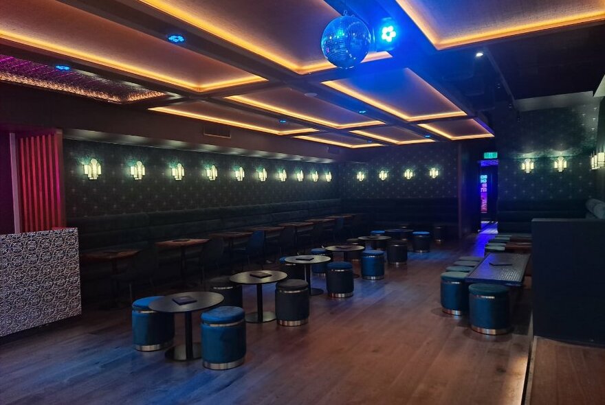 Table seating in a basement bar with mirror ball and subdued lighting.