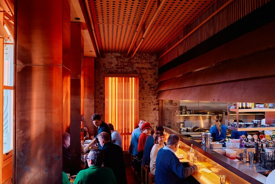 Interior of restaurant space: patrons seated along left, as well as on bar to right. 