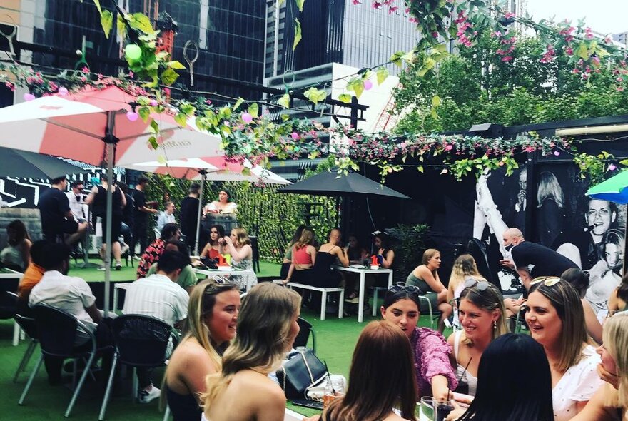 A busy rooftop bar daytime, with people at tables socialising and drinking.