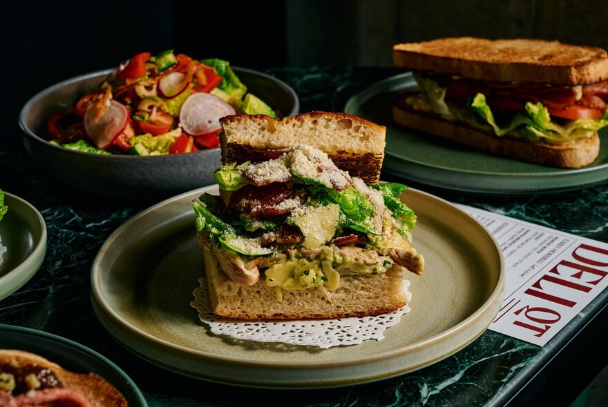 Filled panini, toasted sandwich and bowl of salad on a cafe table with menu.