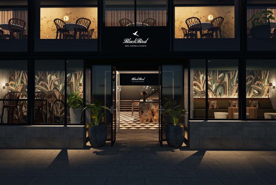 Exterior of Blackbird restaurant at night seen from the street, doors opening onto a black and white tiled entrance foyer.