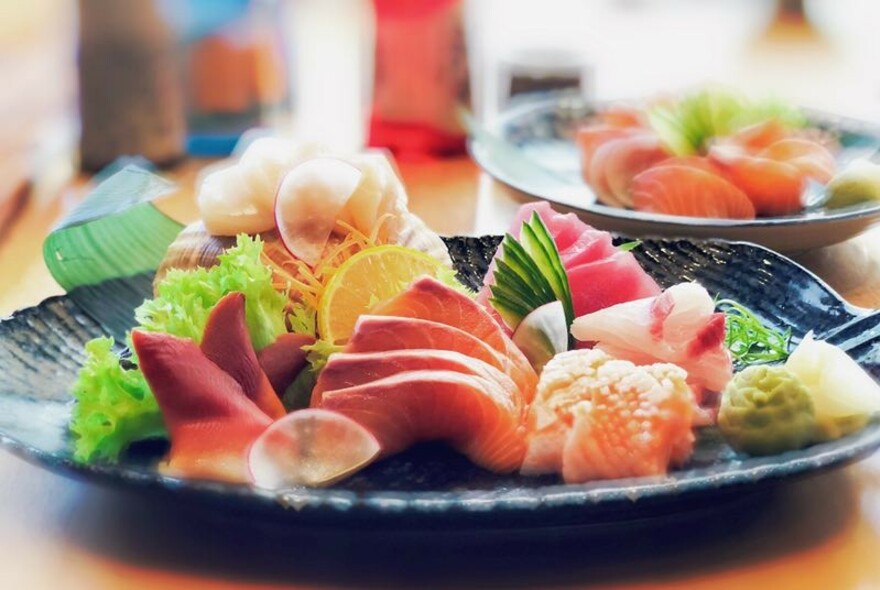 Pottery plate with artfully sliced sashimi and condiments.