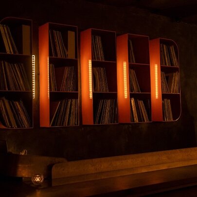 A wall of vinyl records in cube shelving, dimly lit.