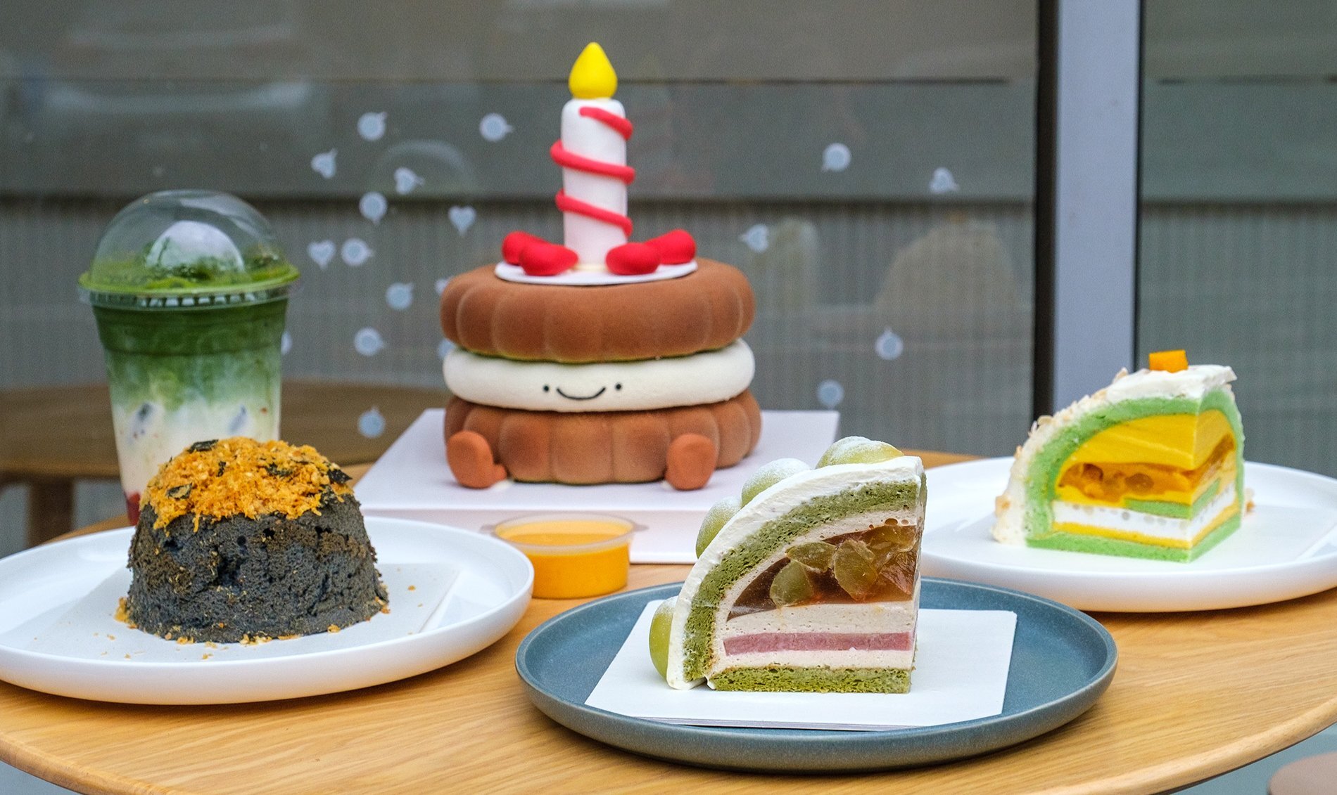 Colourful cakes including one with a candle, legs and smiley face. 
