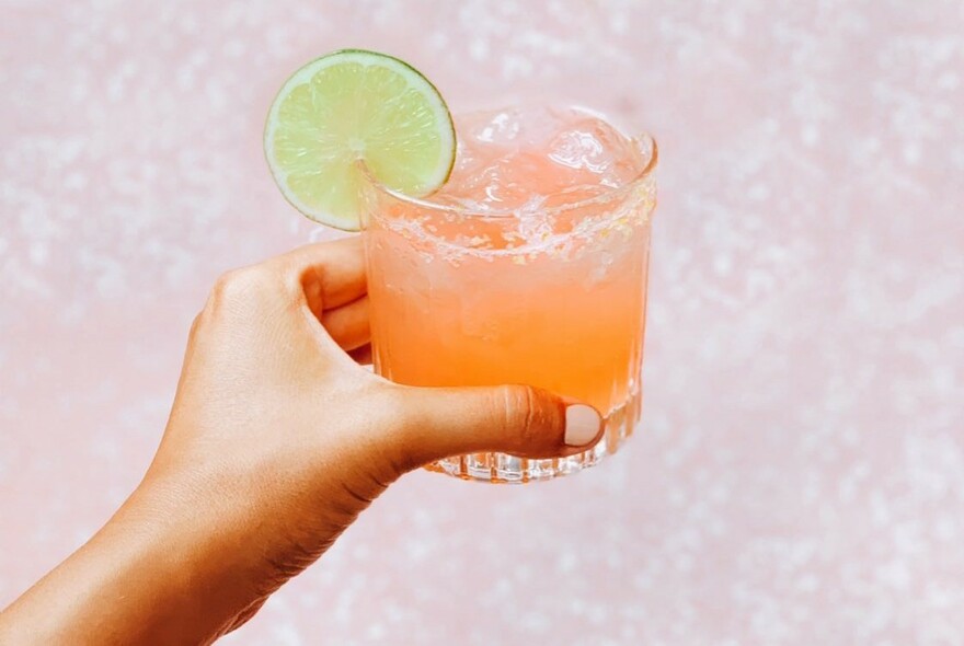 Orange-coloured cocktail with a slice of lime.