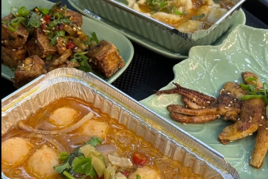 Selection of Chinese food on plates and takeaway containers, including soup and stir fries.