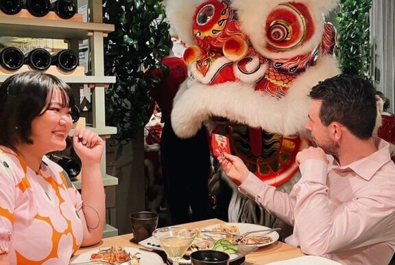 Two diners at a restaurant watching a traditional Chinese lion dance performance. 