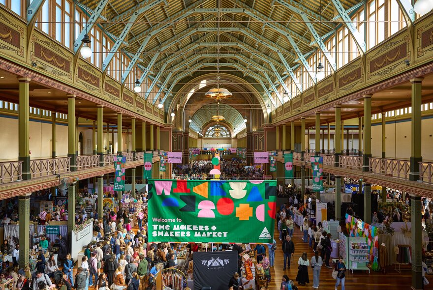 Large colourful banners hanging above a crowd of people in an exhibition hall.