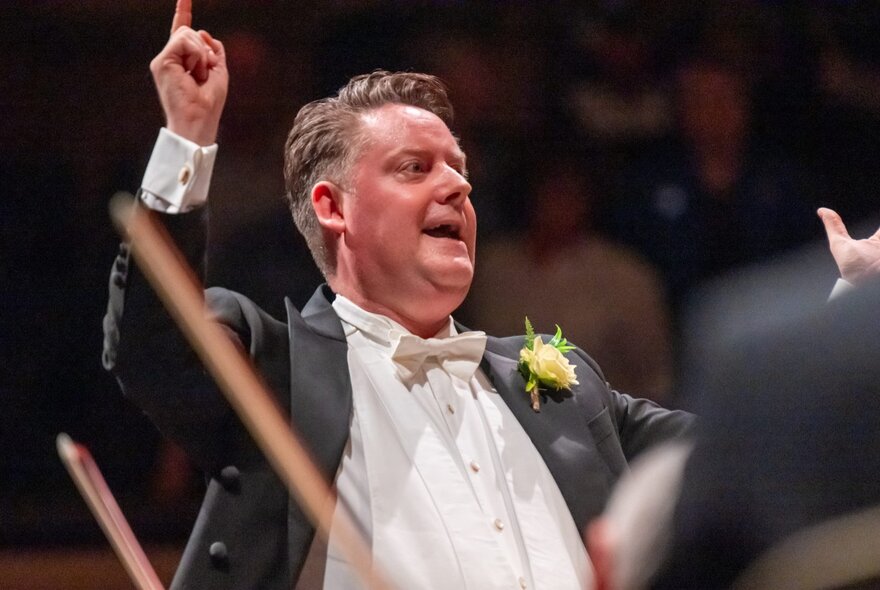 Conductor wearing evening dress leading the orchestra.