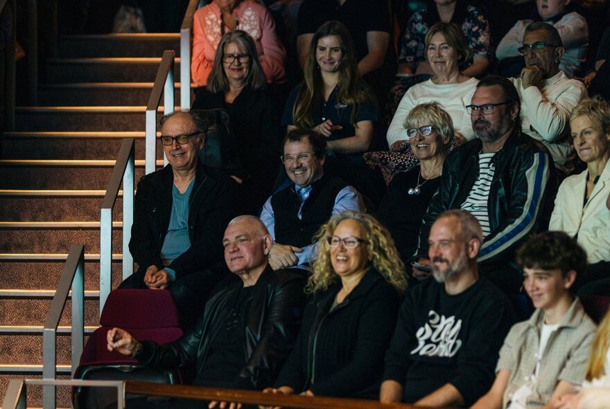Seated audience in a dark venue, looking ahead at a screen.