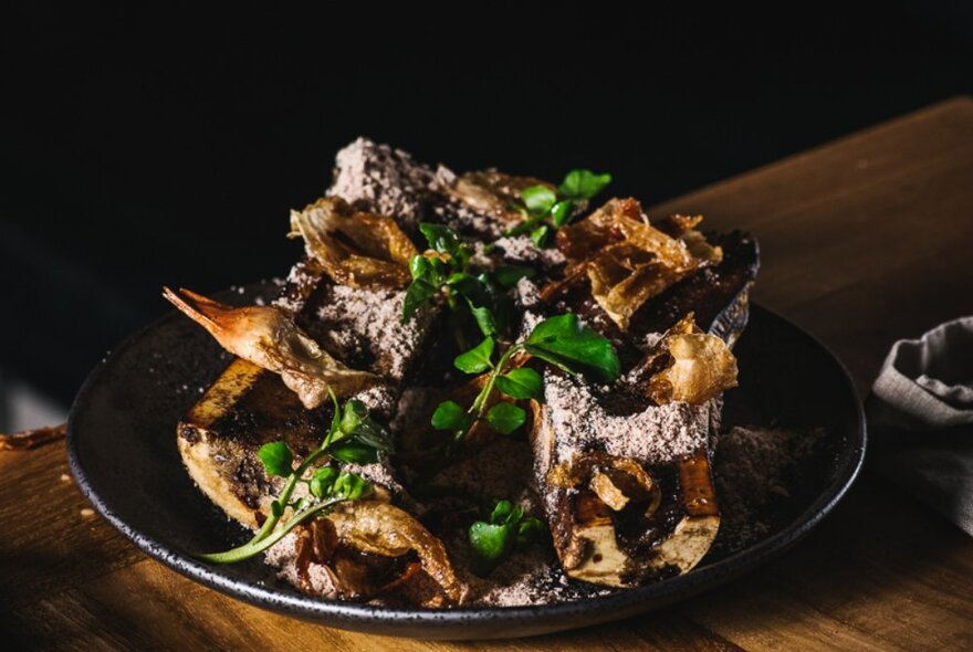 A Viking-style meat dish with a green leafy garnish served on a black dish.