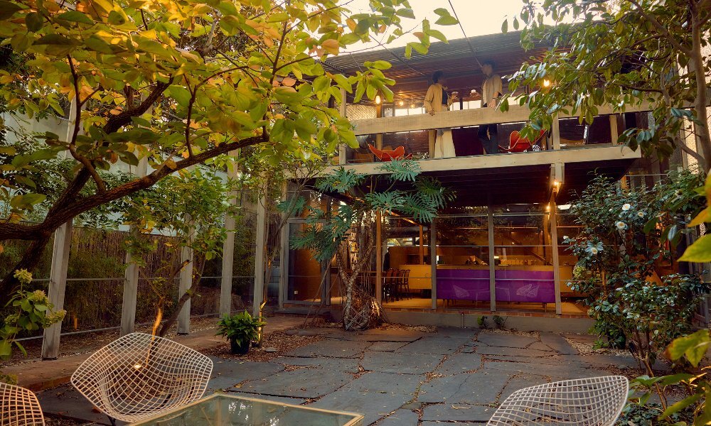 Two friends are sipping cocktails on the balcony of a 1960s home.