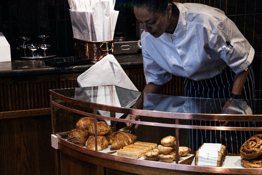 Person looking at pastries in a display cabinet.