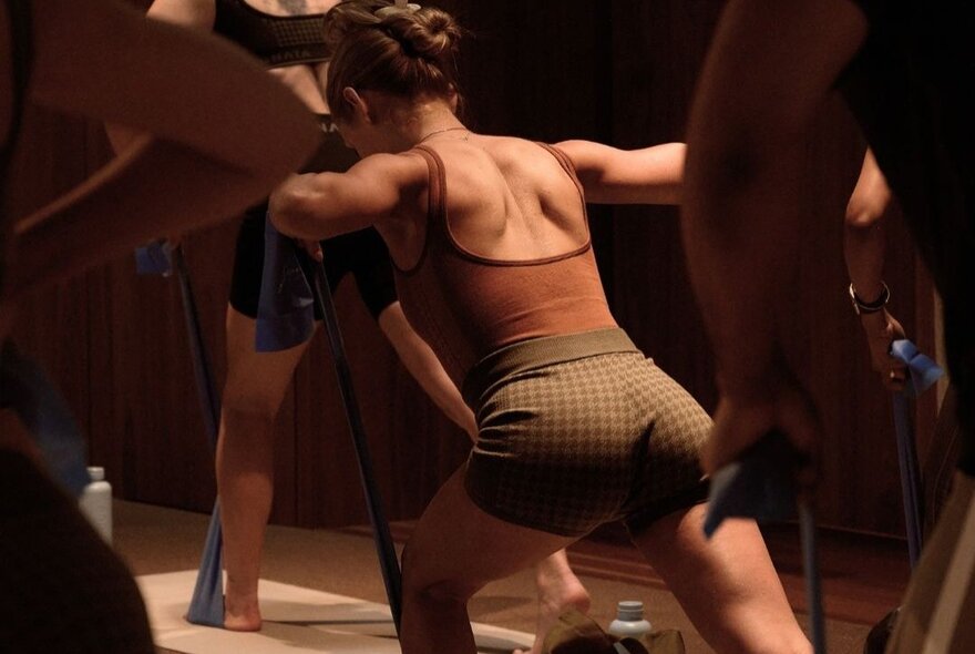 People wearing exercise clothing lunging during an exercise class.