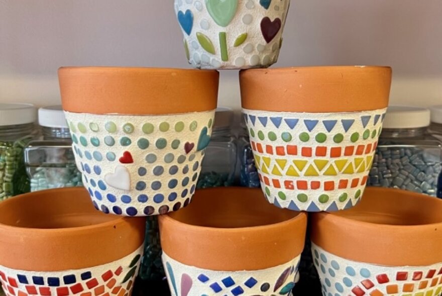 A stack of brightly coloured mosaic-covered terracotta pots.