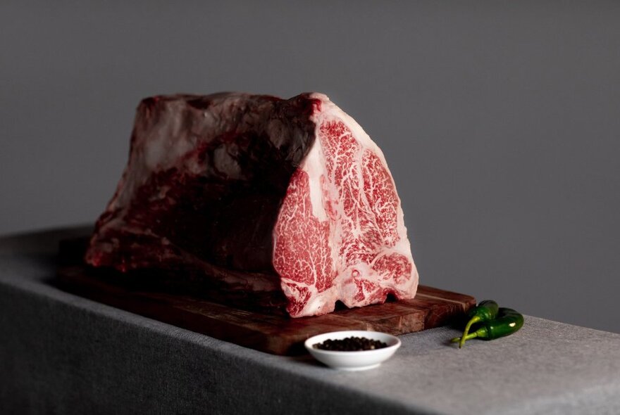 Large slab of raw wagyu beef on a counter with condiments.