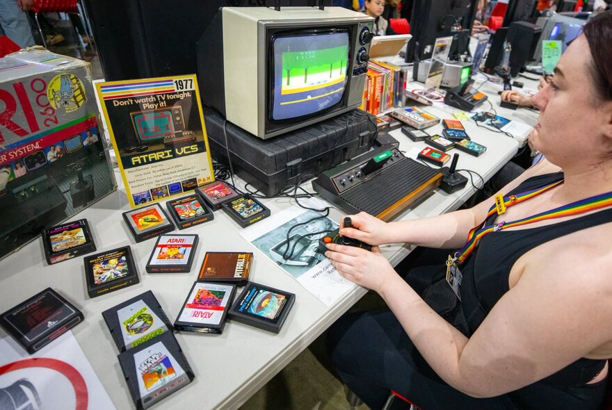 A person playing a vintage Atari 2600 at a retro gaming display at the PAX Australia expo.