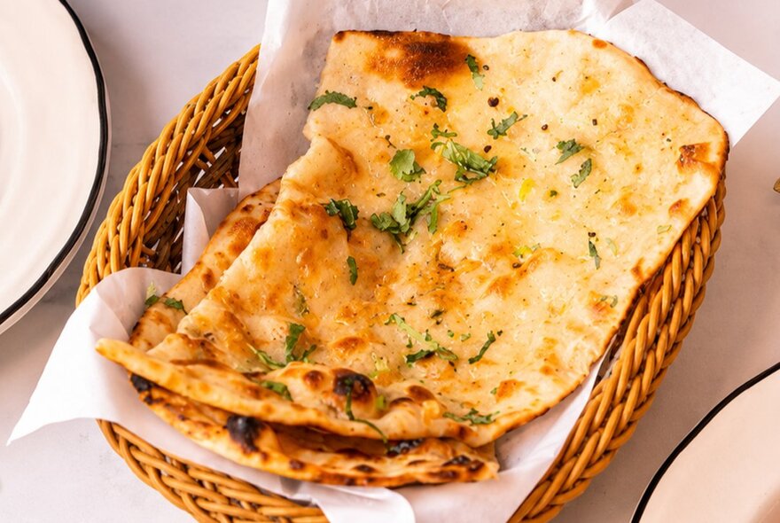 A basket of naan flatbread on a table at an Indian restaurant.