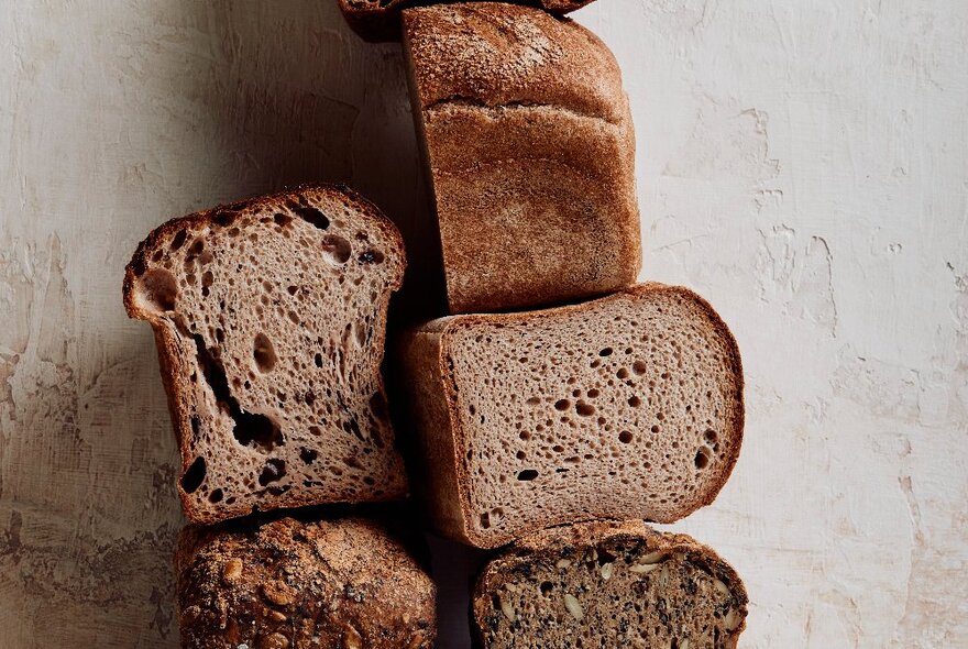 Half cut loaves of bread piled high against a wall.