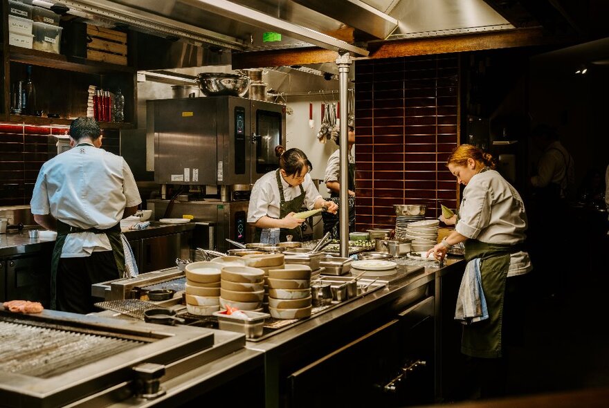 Chefs preparing food in a busy restaurant kitchen.