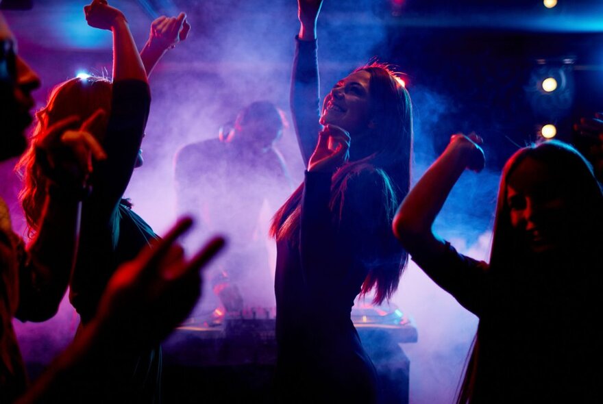 People dancing against purple misty lighting.