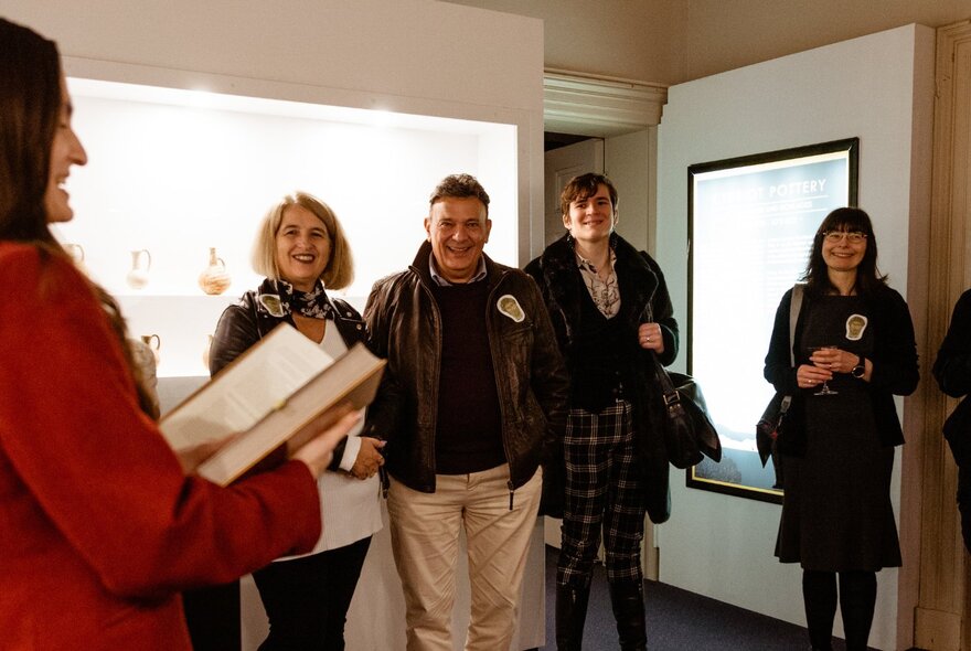 People standing around listening to a talk inside the Hellenic Museum.