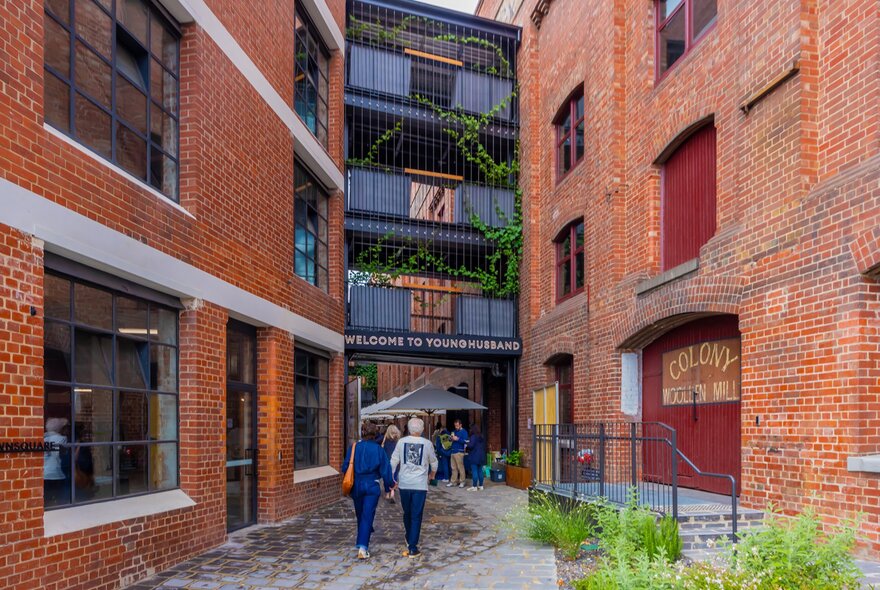 Two people walking into a market in a large brick building.