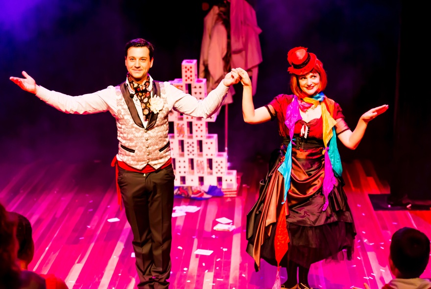 Two performers wearing bright costumes on a stage.