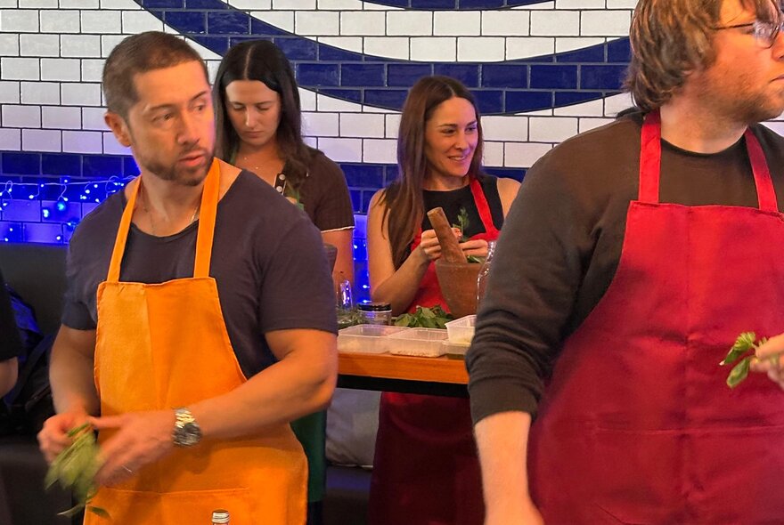 Four people wearing aprons as they participate in an Italian cooking class.
