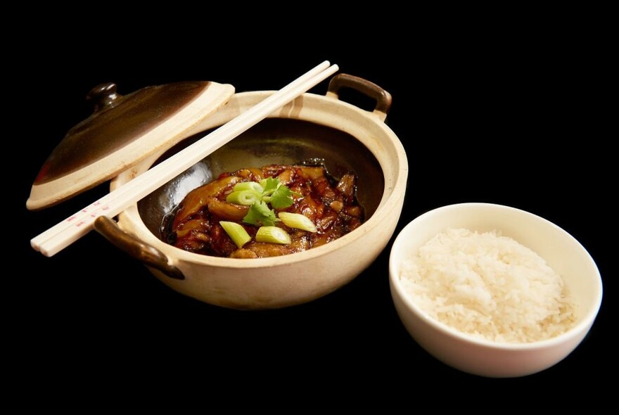 Bowl of food with chopsticks and rice.