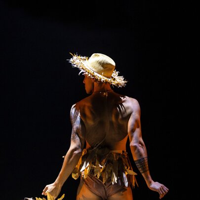 A dancer viewed from behind, wearing a hat.