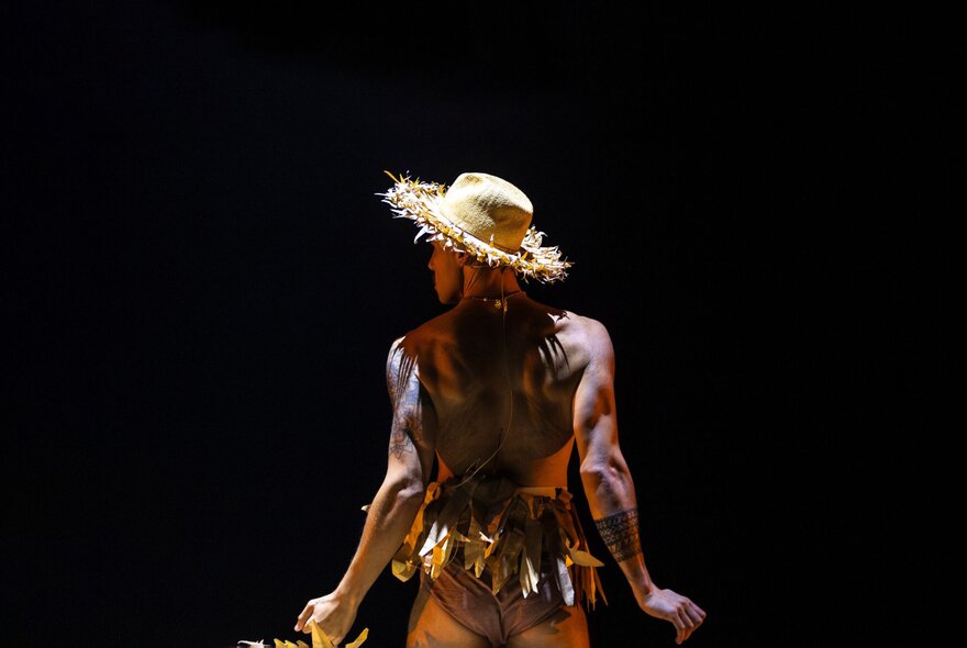 A dancer viewed from behind, wearing a hat.