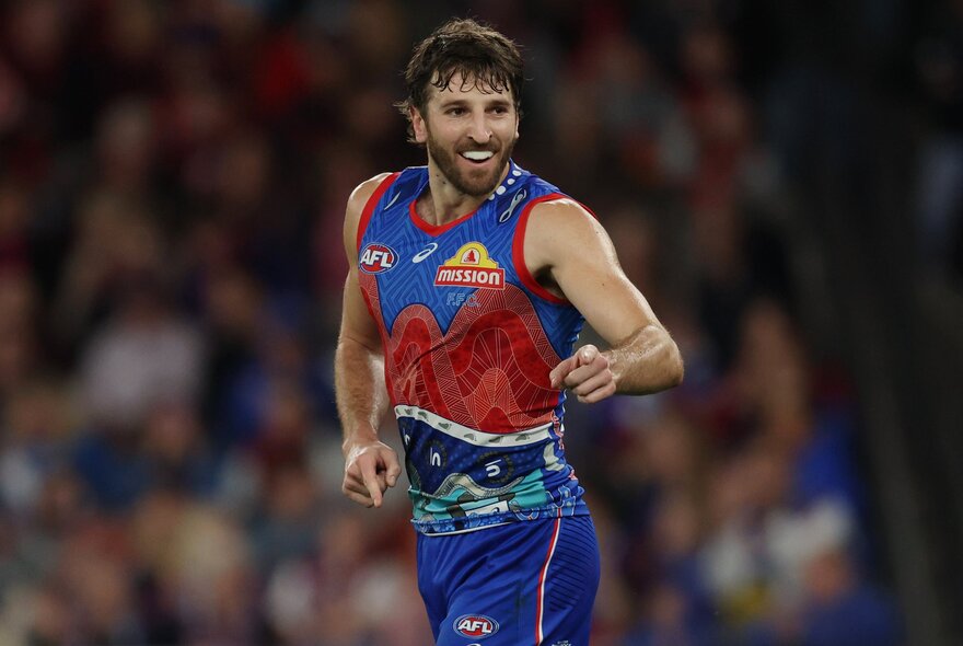 A Western Bulldogs AFL football player running on the footy field during a match.