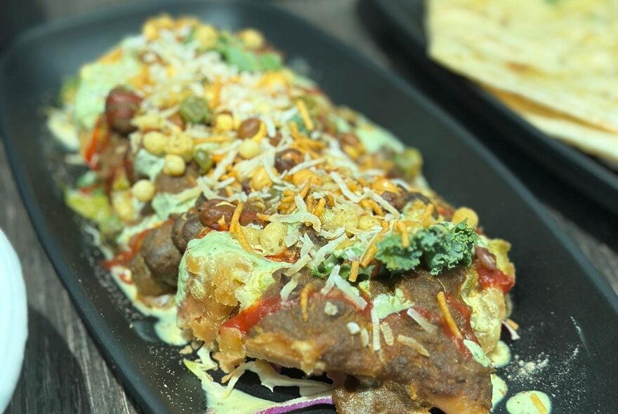 A shared dish of Indian food, with sauce and dried coconut over the top.