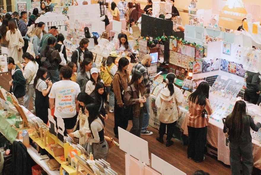 People shopping at an undercover art and stationery market, seen from above.