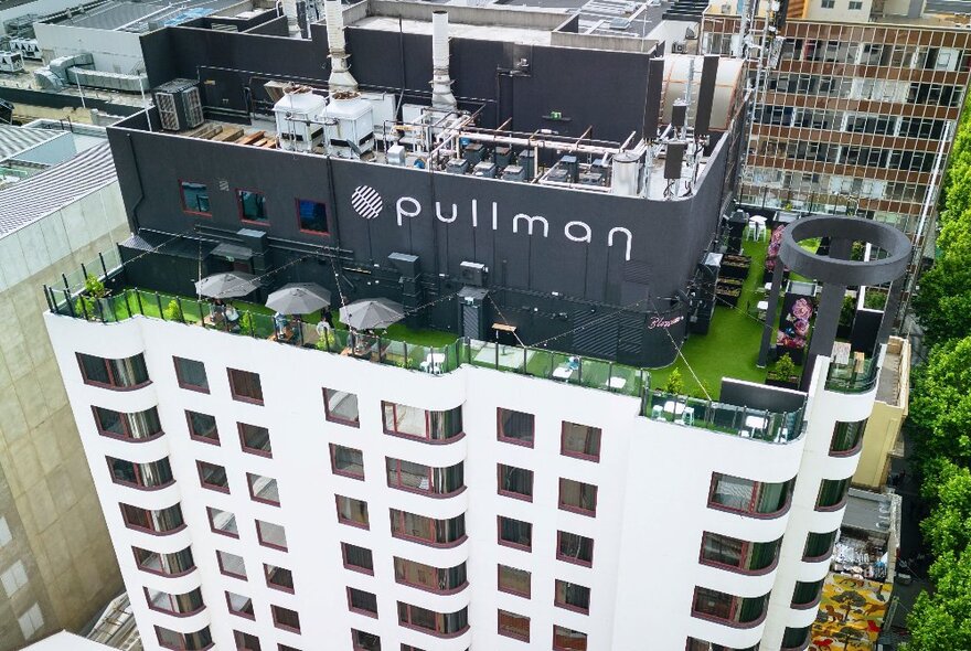 View of hotel rooftop with astroturf and view of top storeys and signage.