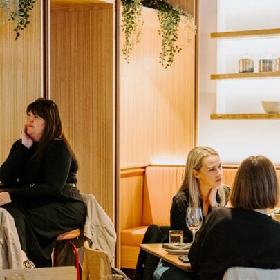 People seated at tables in a lightly lit restaurant with wood details.