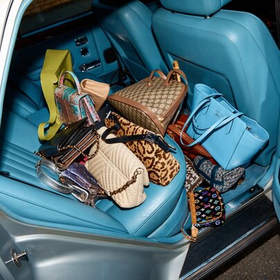An open car door showing aqua coloured leather upholstery and lots of designer bags. 