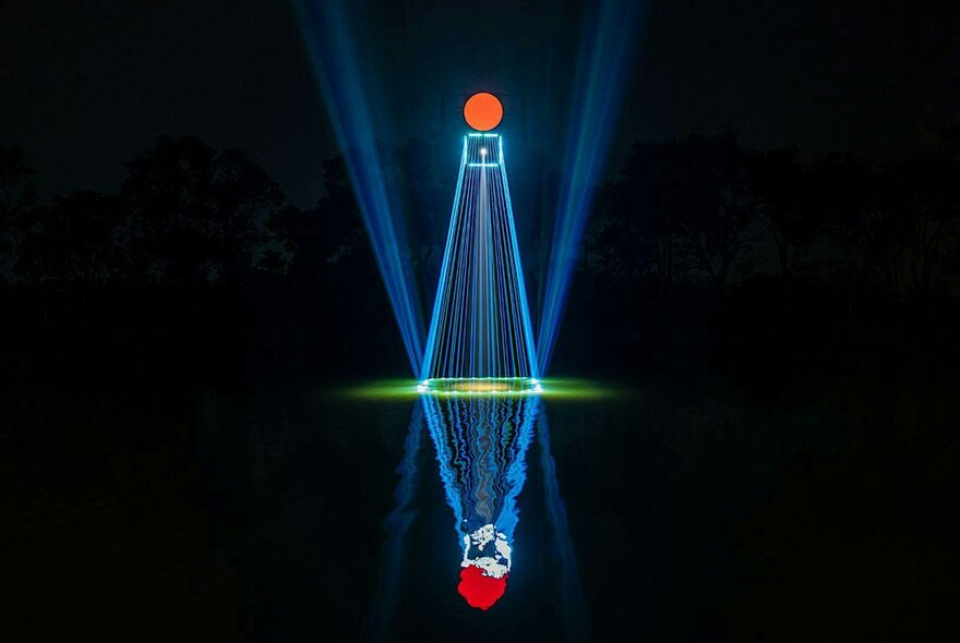 Blue laser beam with a red circle on top are reflected across the water’s surface.