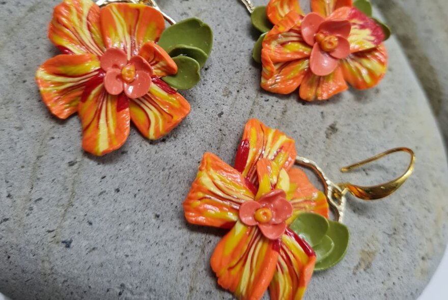 Orange coloured flower petal shaped earrings, made from polymer clay.