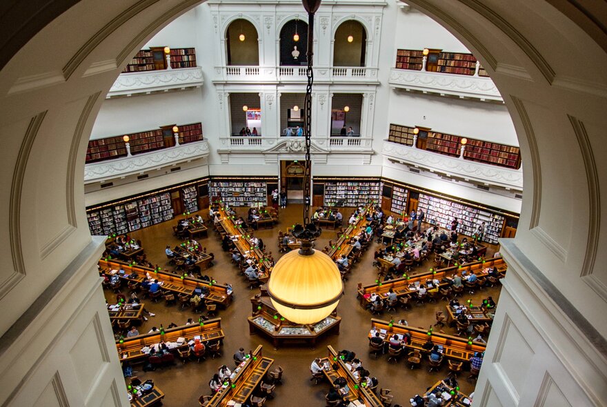 View from one of the alcoves overlooking the La Trobe Reading Room at State Library of Victoria. A lamp is hanging from the top of the alcove.