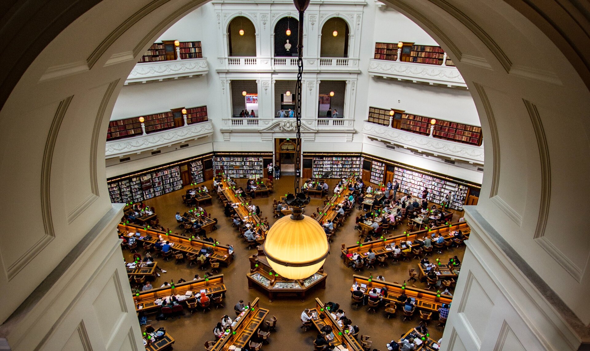 View from one of the alcoves overlooking the La Trobe Reading Room at State Library of Victoria. A lamp is hanging from the top of the alcove.