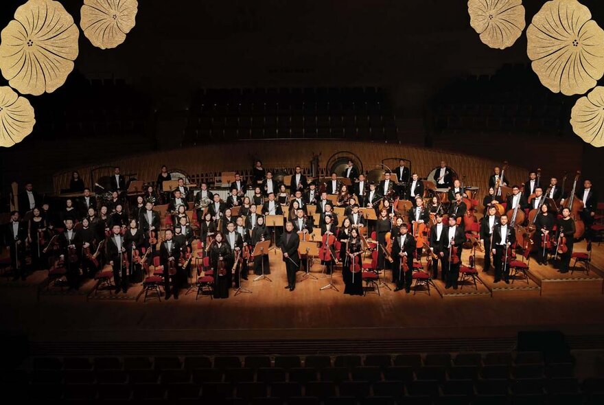 Looking down at the Shanghai Symphony Orchestra with flowers in the top left and right corners. 