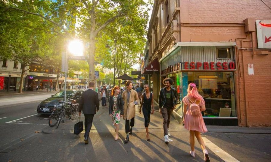 A group of work friends walking past a restaurant at sunset